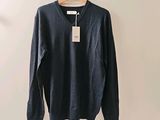 Le pull est suspendu à un cintre accroché au mur.