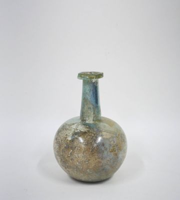 un petit vase en verre avec un couvercle vert posé sur une surface blanche