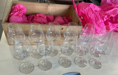 Plusieurs verres à vin vides sont posés sur une table, à côté d'un sac rose.