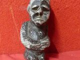 une vieille statue représentant un homme assis sur un tissu rouge