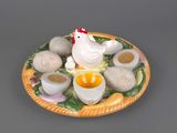 a plate with eggs, eggshells, and a chicken on it