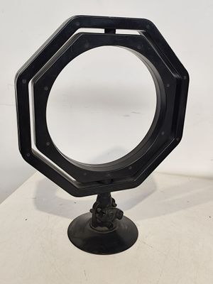 un miroir octogonal noir posé sur un pied, sur une table blanche