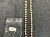 un gros plan d'un collier de perles posé sur une table à côté d'un sac en plastique