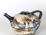 a teapot with a painting on it sitting on a table