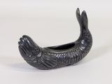 a black fish shaped container on a white surface