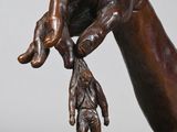 bronze statue of a hand holding a dead bird on a marble base