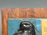 a plaque with a bird on it on a wooden stand