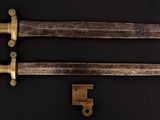 pair of antique brass - plated daggers on a black background