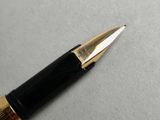 a black and gold pen sitting on a white surface