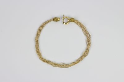 une image représentant un bracelet muni d'un fermoir en or sur fond blanc