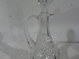 une bouteille en verre transparent avec une poignée sur une surface blanche