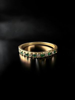 a gold ring with emerald stones on a black background