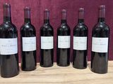 six bottles of wine are lined up on a wooden table