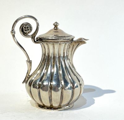 une cafetière en argent posée sur une surface blanche
