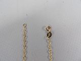 a close up of a pair of gold chains on a white surface