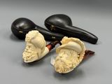 deux têtes de pipe sculptées posées sur une table, à côté d'une paire de chaussures noires