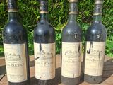 four bottles of wine are lined up on a wooden table