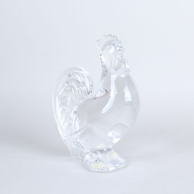 une figurine en verre transparent représentant un coq sur fond blanc