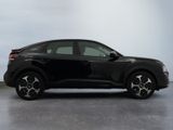 the black car is parked on the concrete floor in the room