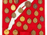 a lot of coins on a red cloth with a white ribbon