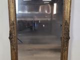 un miroir au cadre doré ouvragé dans une pièce dotée d'un parquet
