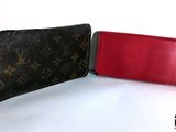 Portefeuille et étui à portefeuille Louis Vuitton posés sur une surface blanche