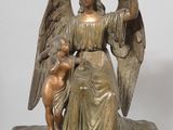 statue of an angel holding a child and a bird on a table