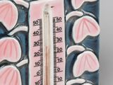 a ceramic thermometer with a red apple on it