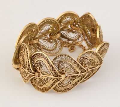 gros plan d'un bracelet en or sur fond blanc