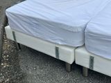 two beds that are covered with white covers on them
