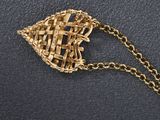 a gold necklace with a woven basket on it