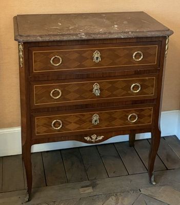 a wooden chest of drawers with a marble top