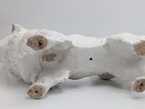 a white ceramic sculpture of a cow laying down