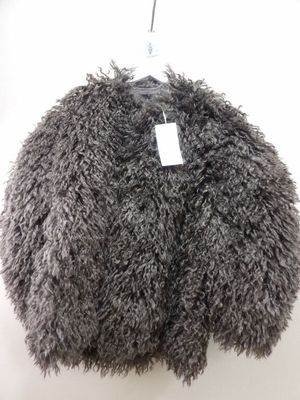 un manteau gris duveteux suspendu à un cintre sur un mur blanc