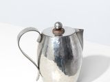 une image représentant une théière en argent posée sur une table blanche