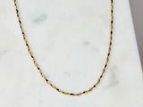 a photo of a gold chain necklace on a marble surface