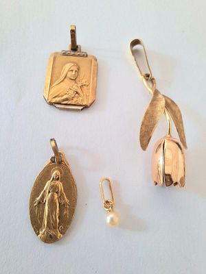 three pieces of jewelry including a gold medal, a pendant, and a pearl