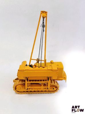 un petit bulldozer jaune posé sur une surface blanche