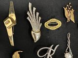 some gold and silver brooches and other jewelry on a black surface