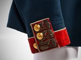 a close up of a blue jacket with gold buttons and a red belt