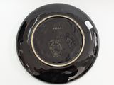 a black plate with a gold rim sitting on a white surface