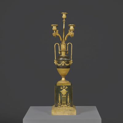 une image représentant un vase doré et noir posé sur un socle blanc