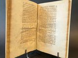 an open book sitting on top of a metal stand on a table