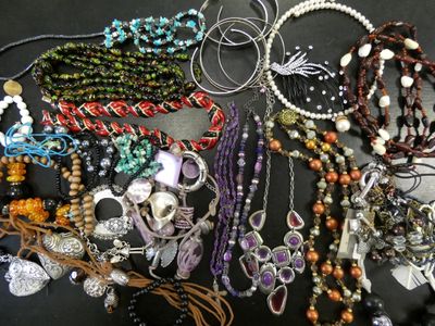many different necklaces and bracelets laid out on a table