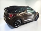 the rear end of a brown car with a black roof