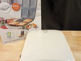 un grille-pain blanc posé sur une table à côté d'une boîte de nourriture