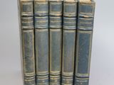 six blue books are lined up in a row on a white surface