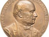 une image représentant une médaille de bronze sur laquelle figure un homme portant un nœud papillon