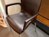 a brown chair sitting in front of a book shelf