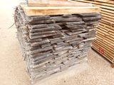 a pile of wood sitting on the ground next to a pile of pallets
